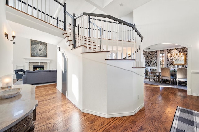 stairway featuring a towering ceiling, a chandelier, and hardwood / wood-style flooring