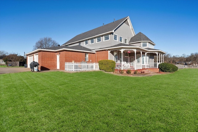 rear view of property featuring a garage, a lawn, and a porch