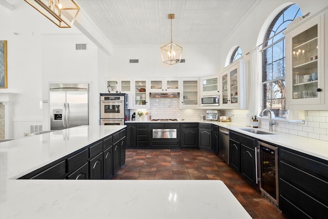 kitchen with backsplash, beverage cooler, built in appliances, white cabinets, and sink