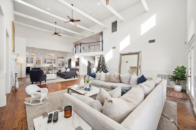 living room with dark wood-type flooring, ceiling fan with notable chandelier, and a high ceiling