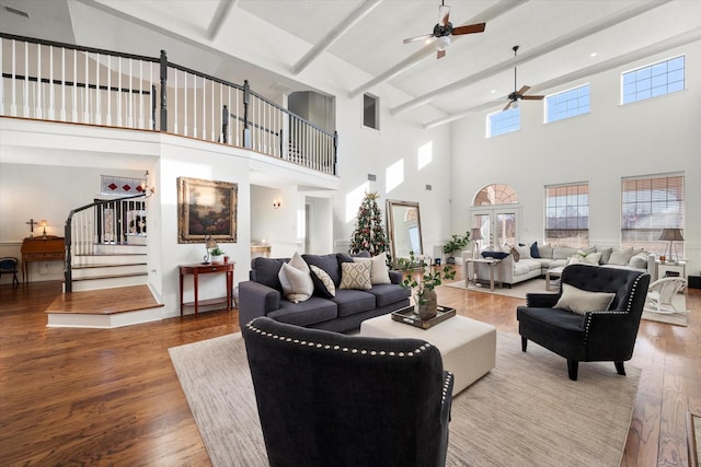 living room featuring ceiling fan, a high ceiling, hardwood / wood-style floors, and beamed ceiling