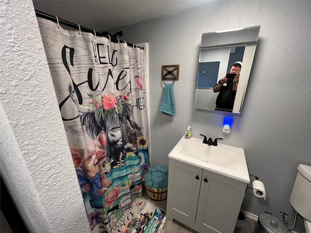 bathroom with toilet, a shower with shower curtain, and vanity