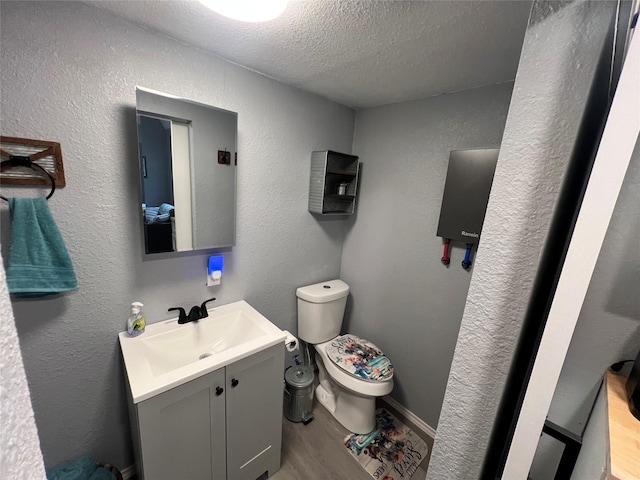 bathroom featuring toilet, wood-type flooring, vanity, and a textured ceiling