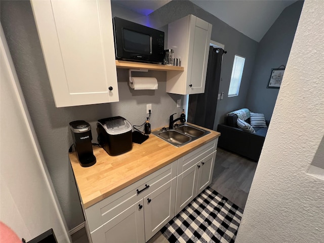 kitchen featuring vaulted ceiling, butcher block countertops, gray cabinetry, and sink