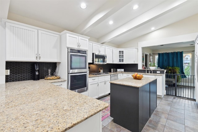 kitchen with white cabinetry, lofted ceiling with beams, kitchen peninsula, and appliances with stainless steel finishes