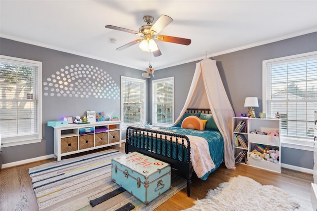 bedroom featuring ornamental molding, ceiling fan, wood-type flooring, and multiple windows