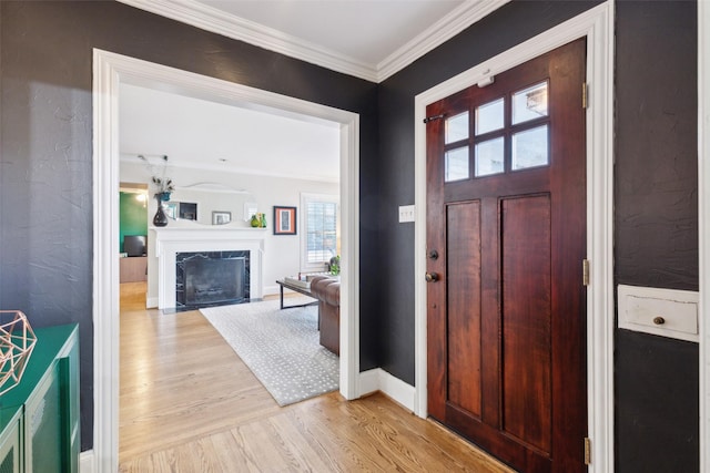 foyer entrance featuring light wood-type flooring, crown molding, and a fireplace