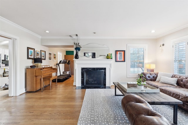 living room with a premium fireplace, ornamental molding, and light hardwood / wood-style floors