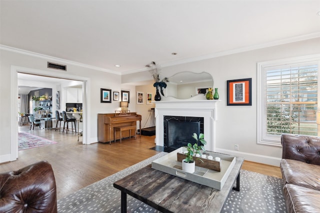 living room featuring ornamental molding, a premium fireplace, and wood-type flooring