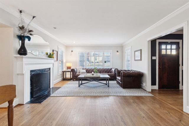 living room featuring a premium fireplace, ornamental molding, and light hardwood / wood-style flooring