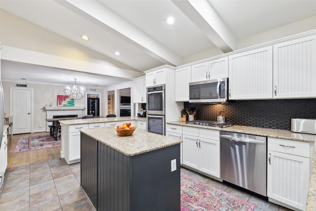 kitchen with appliances with stainless steel finishes, white cabinetry, backsplash, and a kitchen island