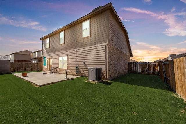 back house at dusk featuring a yard, a patio, and central air condition unit