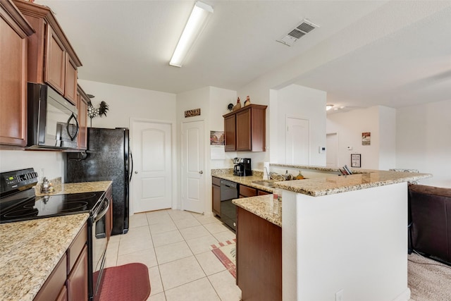 kitchen featuring light stone countertops, a kitchen breakfast bar, black appliances, and light tile patterned flooring