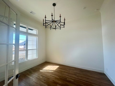 unfurnished dining area featuring dark hardwood / wood-style flooring, plenty of natural light, and an inviting chandelier