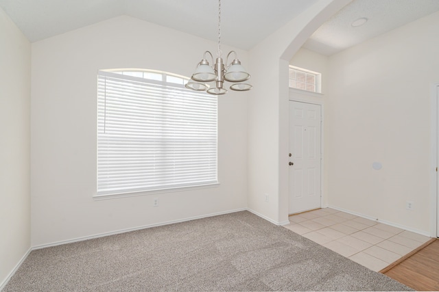 tiled spare room featuring lofted ceiling, an inviting chandelier, and plenty of natural light