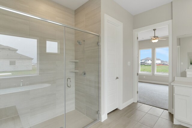 full bath featuring a shower stall, tile patterned flooring, baseboards, ceiling fan, and vanity