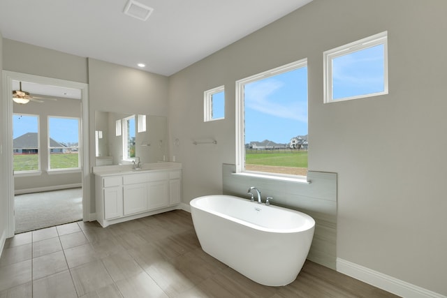 full bathroom featuring visible vents, a freestanding bath, vanity, and baseboards