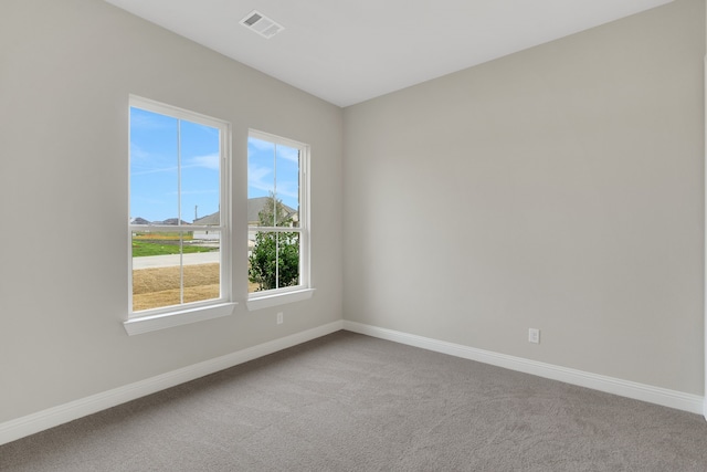 unfurnished room with carpet flooring, visible vents, and baseboards