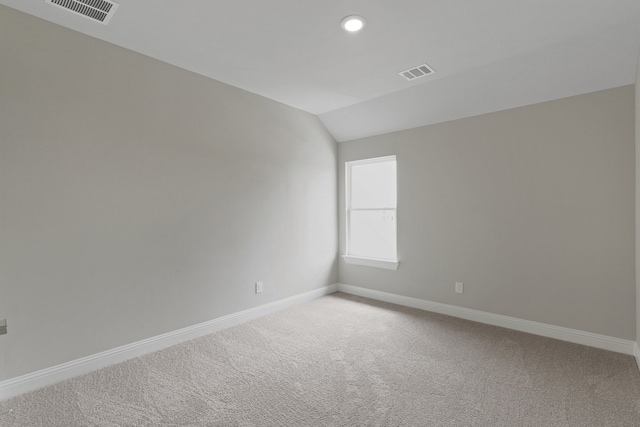 empty room with visible vents, light colored carpet, lofted ceiling, and baseboards