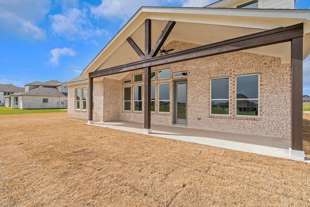 back of property featuring brick siding, a yard, and a patio