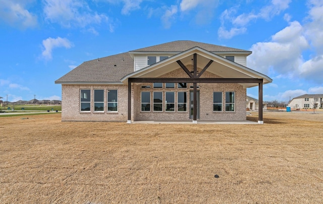 rear view of property featuring brick siding, a shingled roof, a gazebo, a lawn, and a patio area