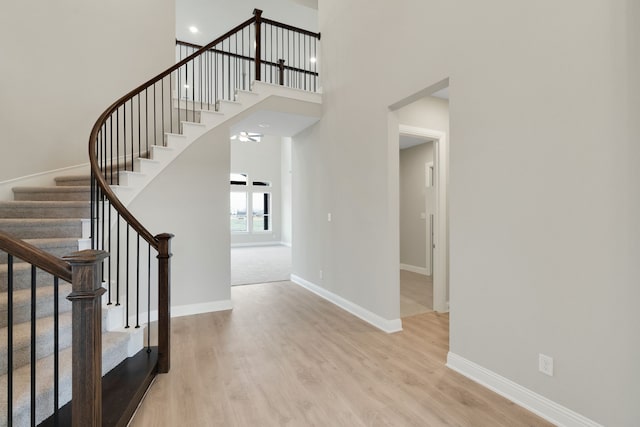 entryway featuring stairway, baseboards, wood finished floors, and a towering ceiling