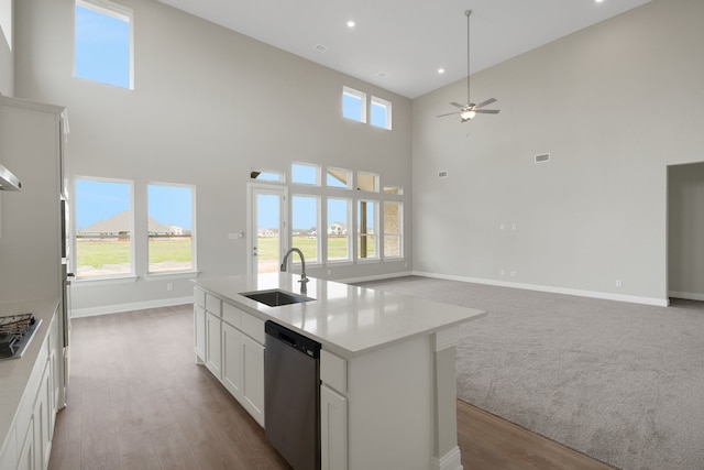 kitchen with baseboards, a sink, white cabinets, appliances with stainless steel finishes, and open floor plan