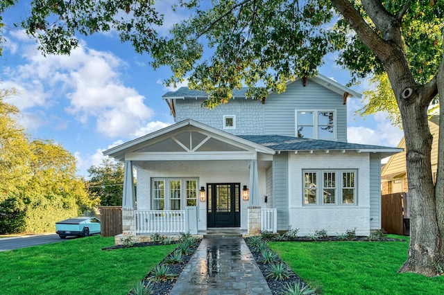 craftsman-style house featuring covered porch and a front lawn