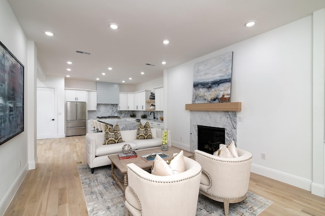 living room featuring sink, light hardwood / wood-style flooring, and a fireplace