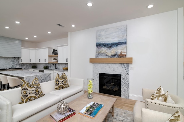 living room with light hardwood / wood-style floors, a premium fireplace, and sink