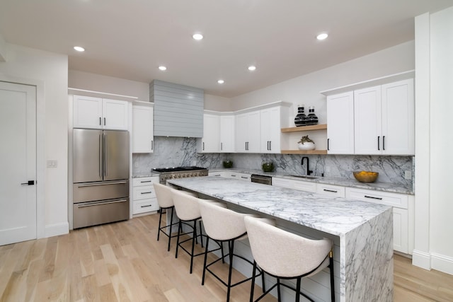 kitchen featuring stainless steel appliances, white cabinets, a kitchen bar, and a center island