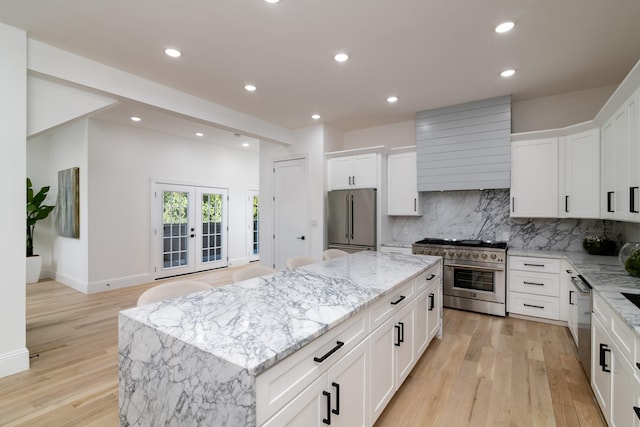 kitchen featuring high quality appliances, white cabinetry, backsplash, and a center island