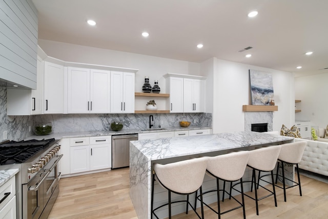 kitchen featuring white cabinets, appliances with stainless steel finishes, a breakfast bar area, and sink