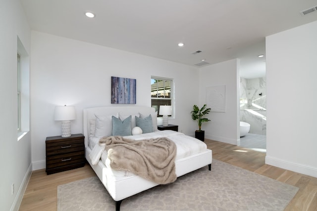 bedroom with ensuite bath and light wood-type flooring