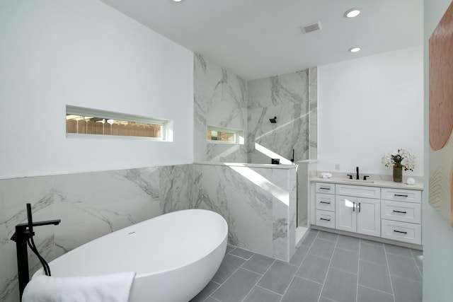 bathroom with tile walls, tile patterned floors, independent shower and bath, and vanity