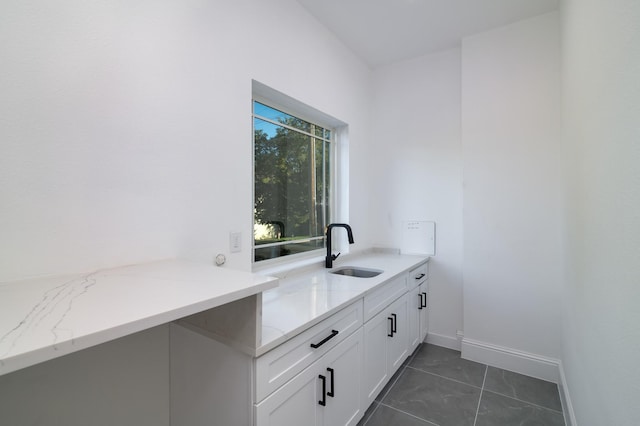 clothes washing area featuring dark tile patterned floors and sink