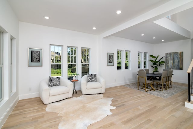 living area featuring light wood-type flooring and beam ceiling