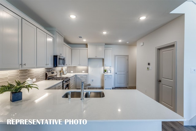 kitchen featuring sink, white cabinets, kitchen peninsula, decorative backsplash, and appliances with stainless steel finishes