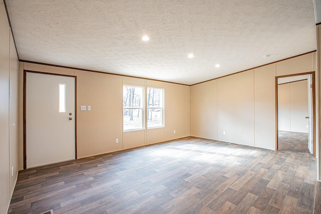 unfurnished room with a textured ceiling, crown molding, and dark hardwood / wood-style floors