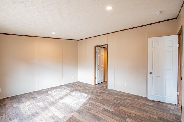 empty room with hardwood / wood-style flooring, a textured ceiling, and ornamental molding