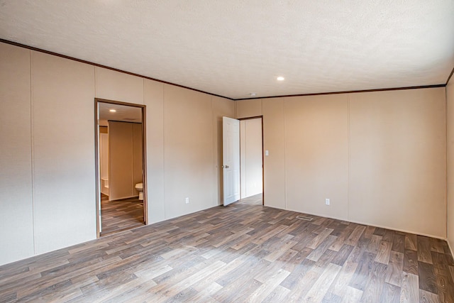 empty room with ornamental molding, a textured ceiling, and hardwood / wood-style flooring