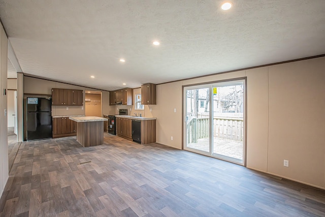 kitchen featuring a textured ceiling, vaulted ceiling, dark hardwood / wood-style floors, black appliances, and a kitchen island