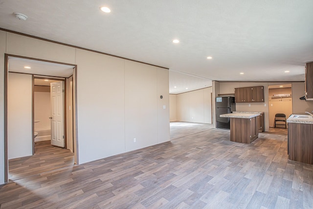 kitchen featuring black refrigerator, wood-type flooring, ornamental molding, a kitchen island, and sink