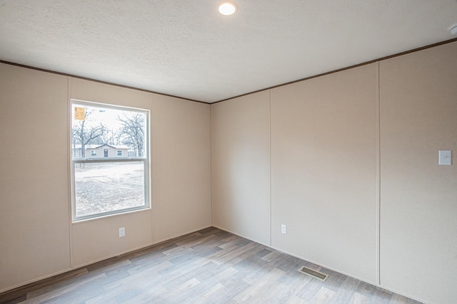 empty room featuring a textured ceiling and light hardwood / wood-style flooring