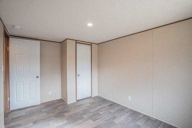 unfurnished bedroom with crown molding and light hardwood / wood-style flooring