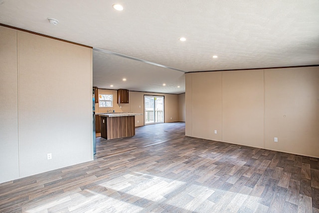 unfurnished living room featuring a textured ceiling, crown molding, and hardwood / wood-style flooring