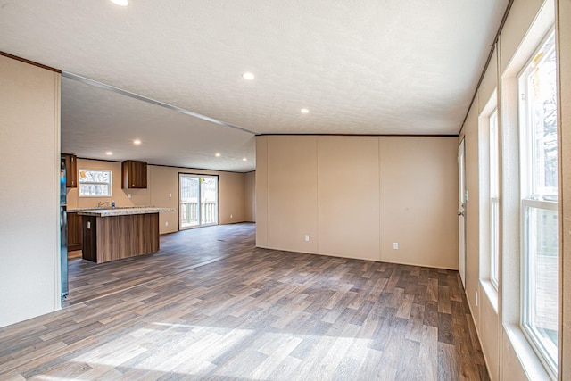 unfurnished living room featuring ornamental molding, dark wood-type flooring, and a textured ceiling