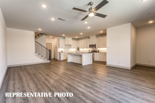 kitchen featuring light hardwood / wood-style floors, a kitchen island with sink, white cabinetry, appliances with stainless steel finishes, and ceiling fan