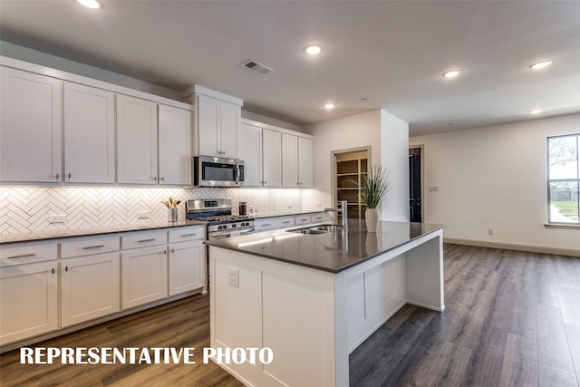 kitchen featuring appliances with stainless steel finishes, white cabinets, a kitchen island with sink, and sink