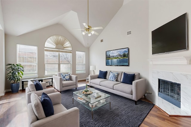 living room featuring ceiling fan, a high end fireplace, hardwood / wood-style floors, and high vaulted ceiling